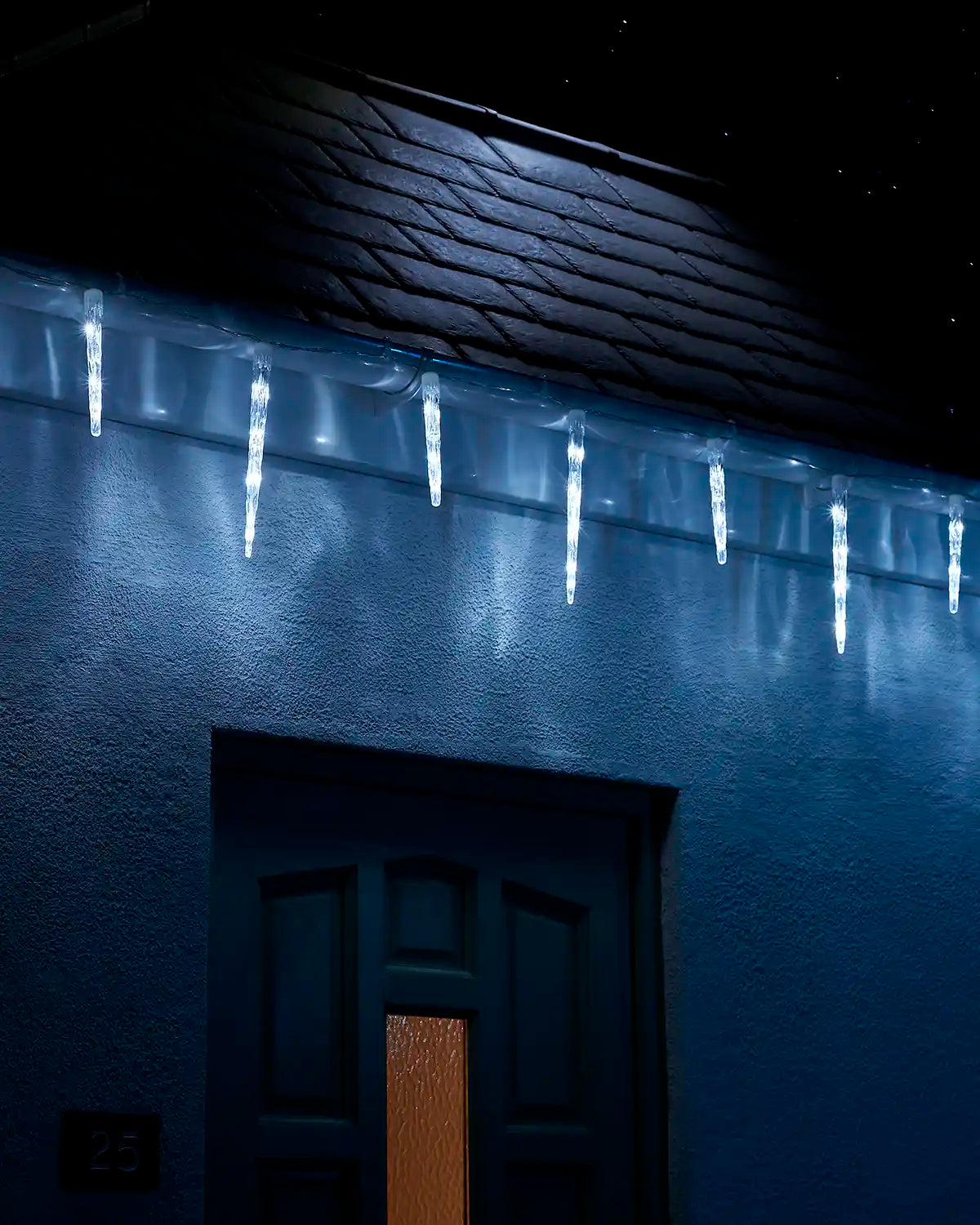 White icicle drop lights hanging above a front door at night.