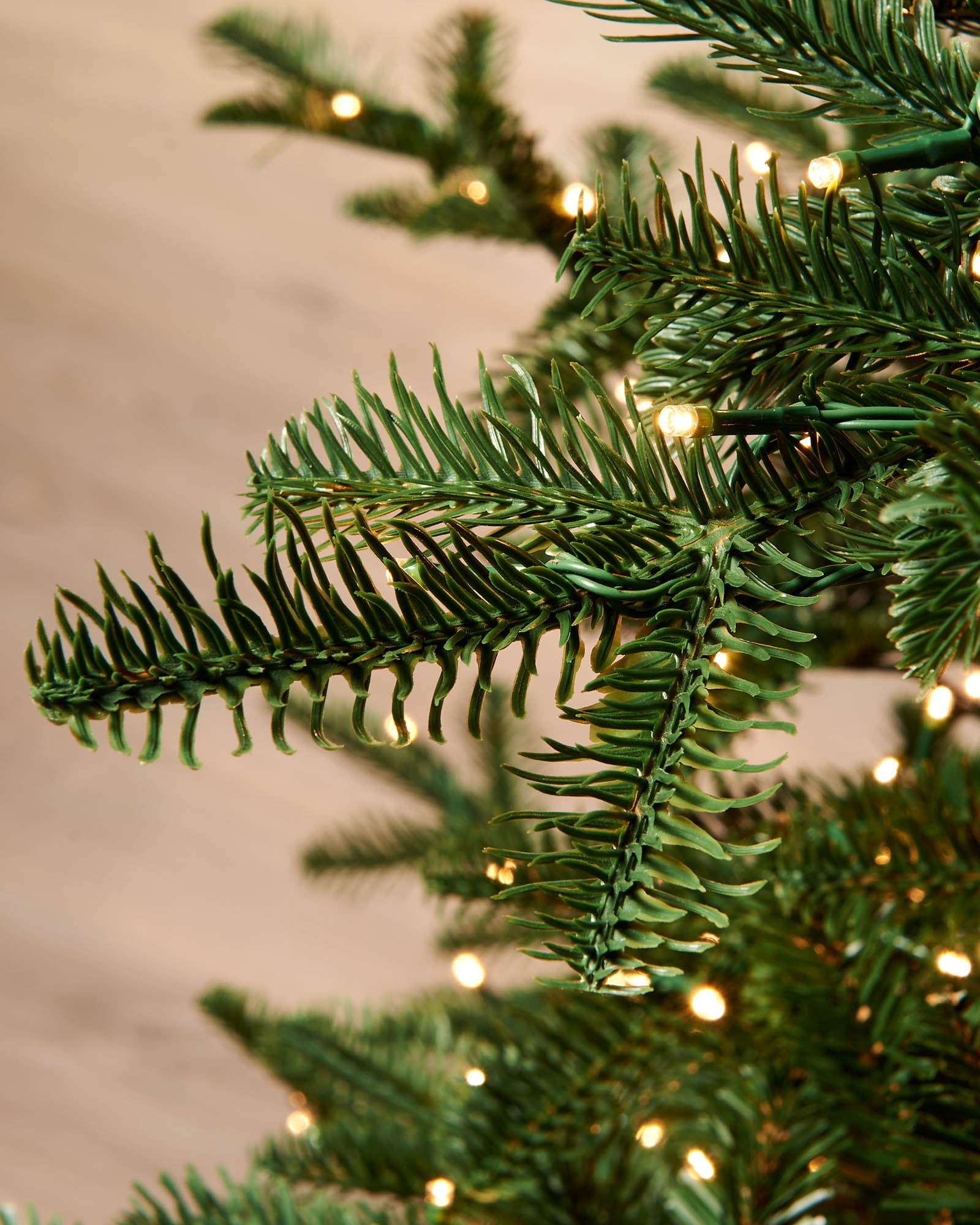 Detail of warm white LED lights woven through realistic green fir branches.