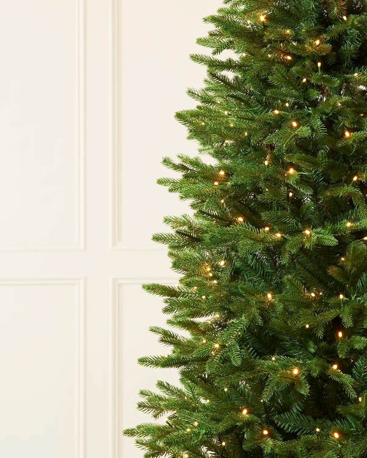 Detailed view of the full green branches and warm white lights on the Christmas tree.