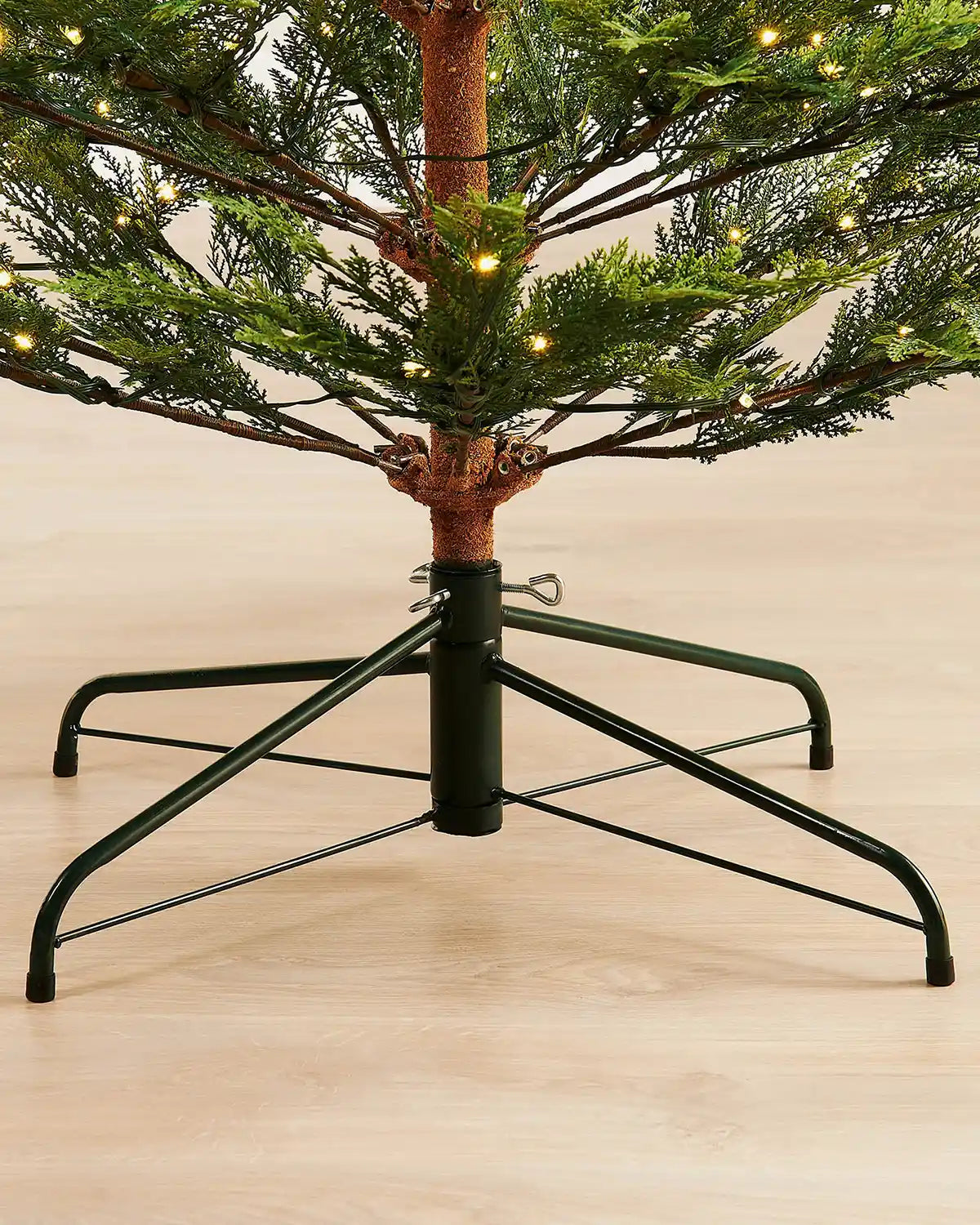 Close-up of 7.5ft pre-lit cypress fir Christmas tree green stand on light wood flooring