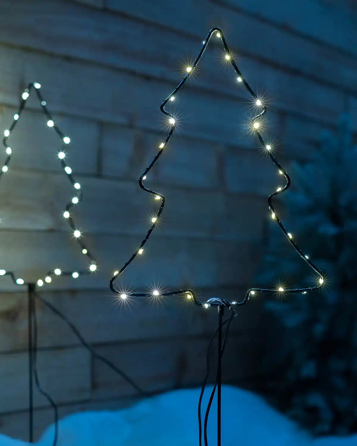Illuminated Christmas tree pathway light displayed outdoors in snow