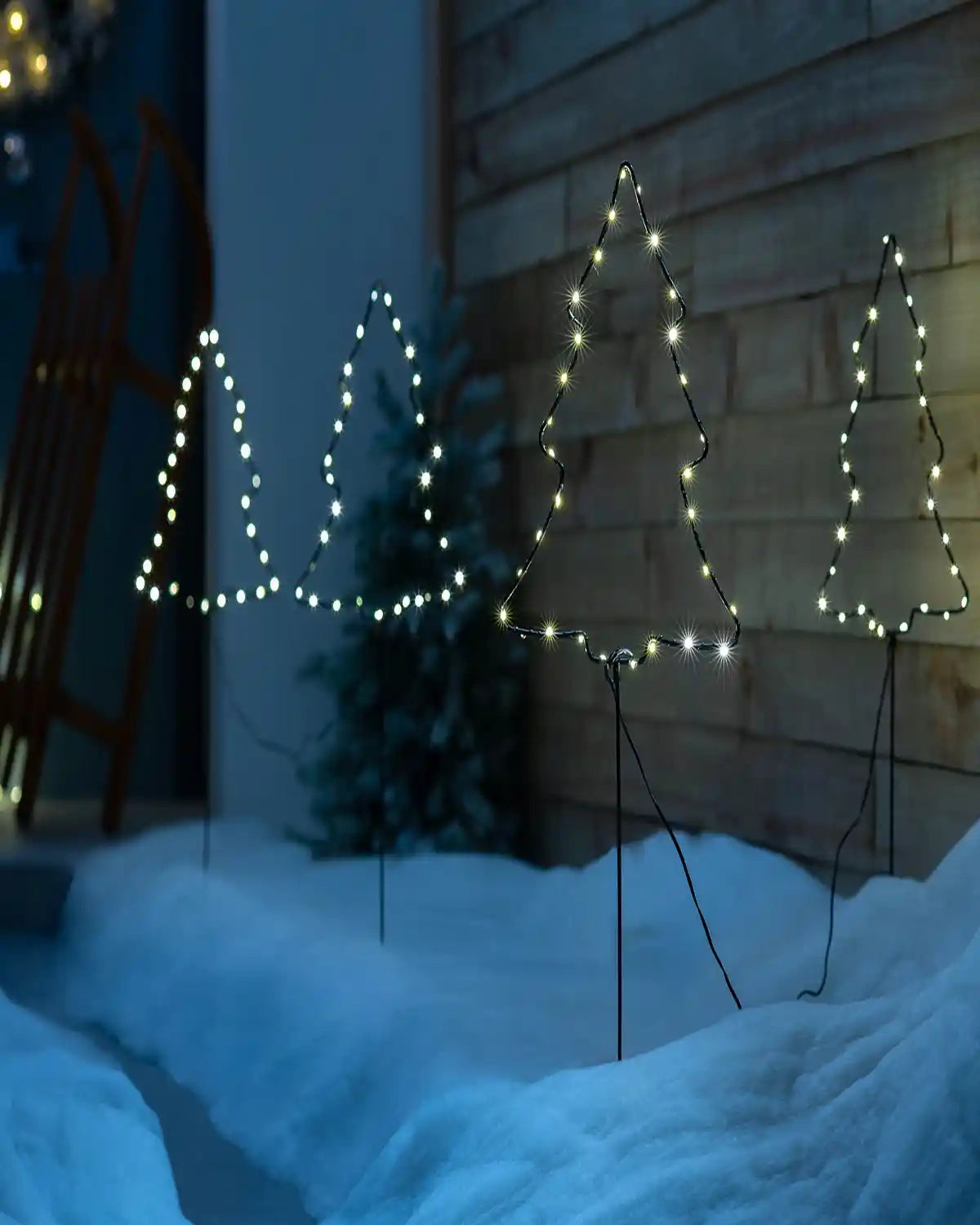 Set of illuminated Christmas tree pathway lights displayed along snowy pathway