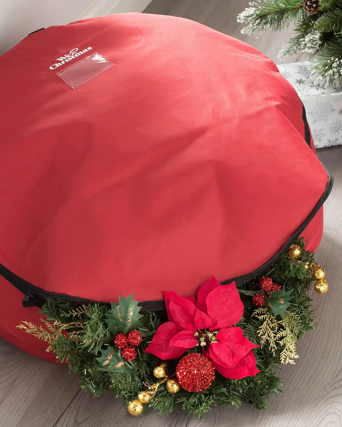 Red garland and wreath storage bag holding a decorated Christmas wreath indoors