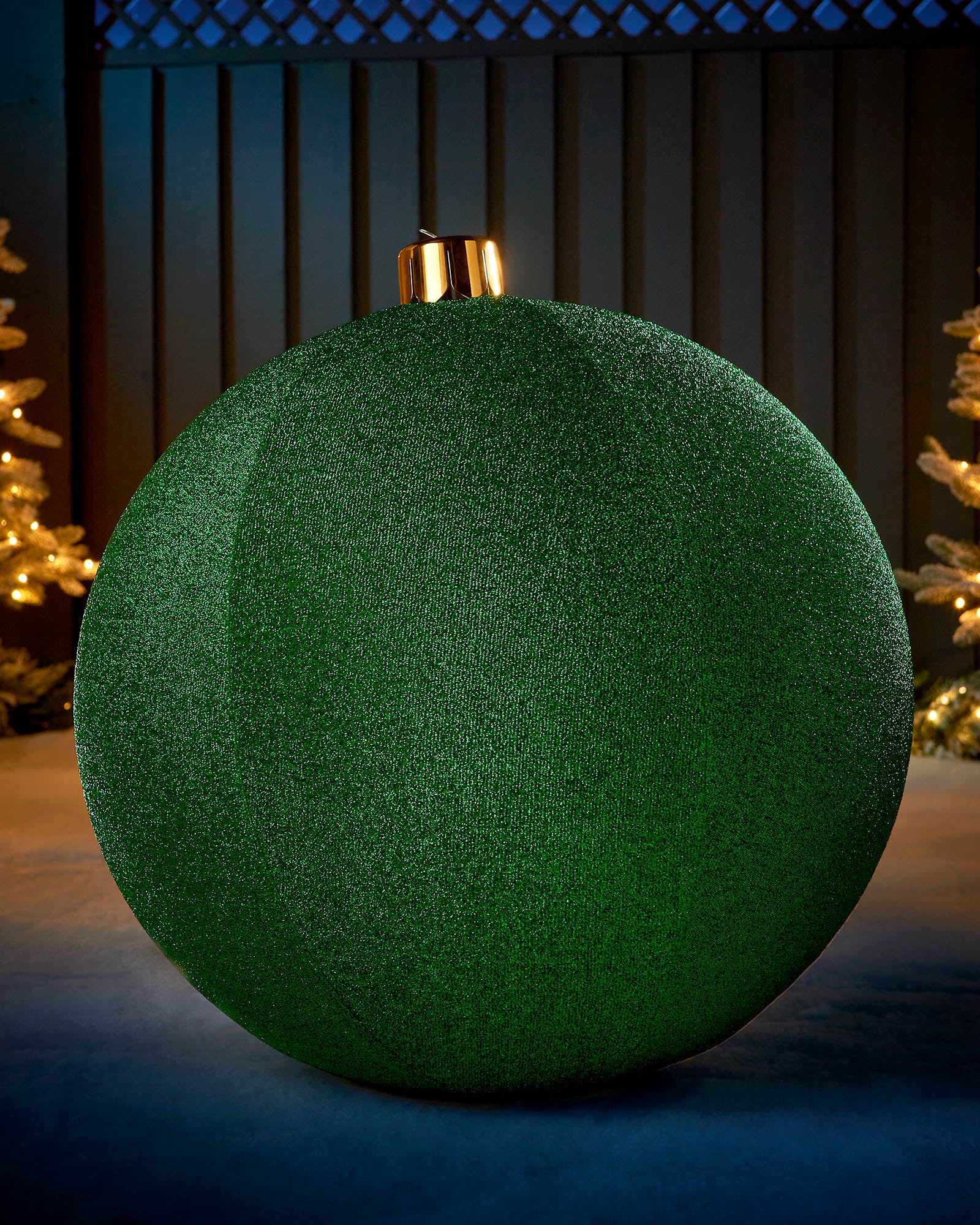 Large green 76cm inflatable tinsel Christmas bauble with a gold cap in an outdoor festive display.