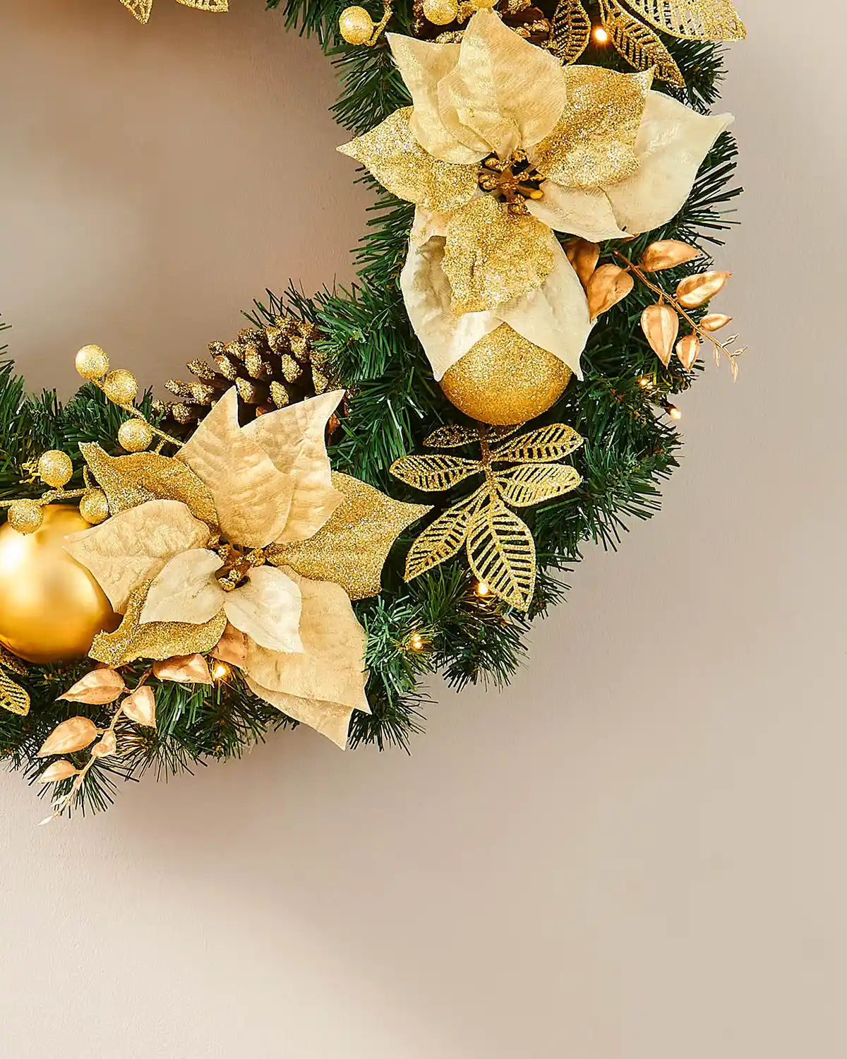 Lower section of the cream and gold pre-lit wreath with flowers, baubles and gold leaves