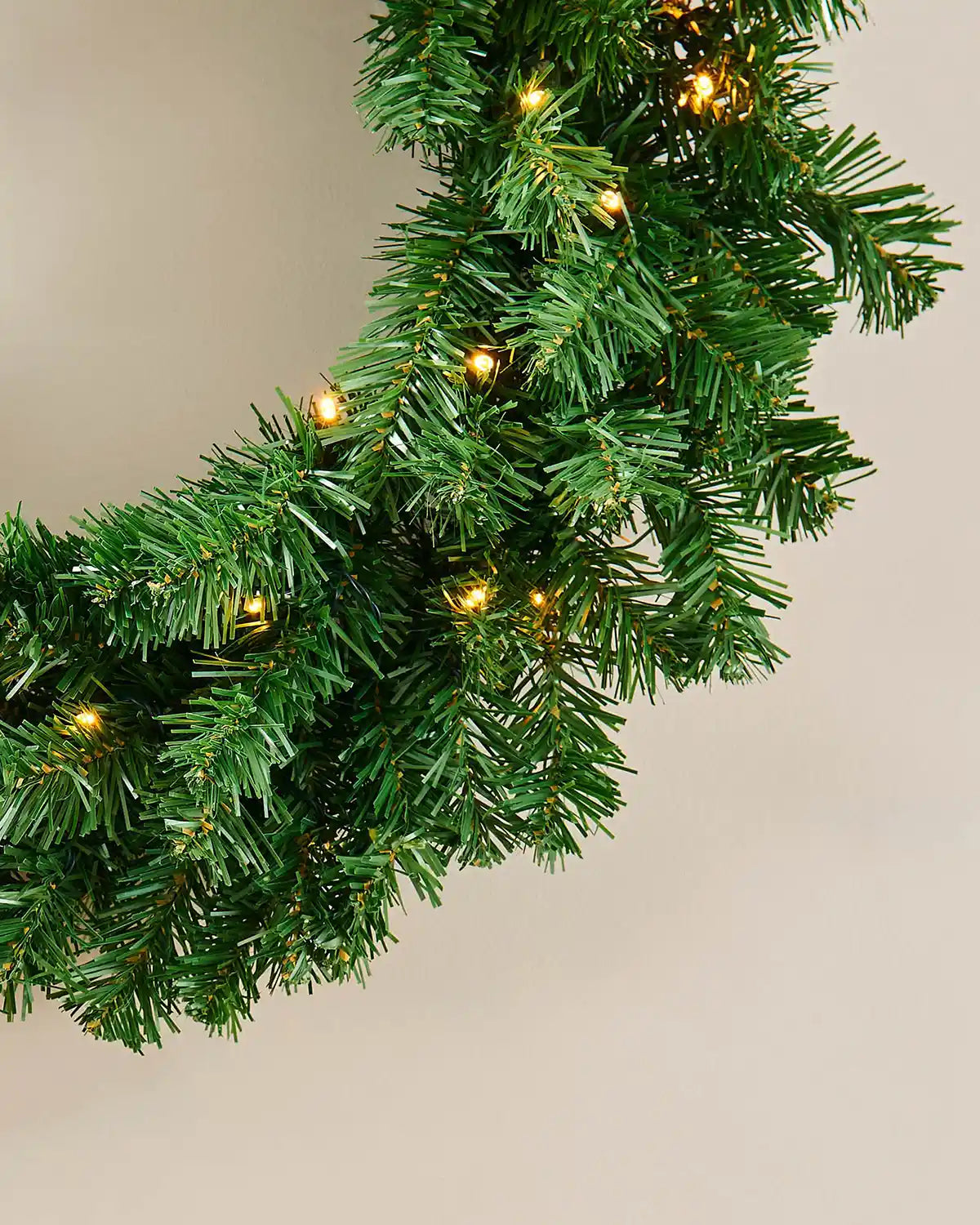 Close-up of warm white LED lights woven through the green Christmas wreath