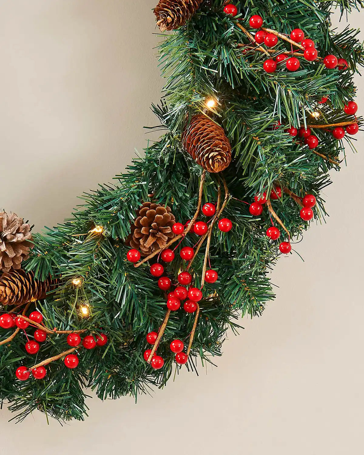 Side detail of the pre-lit Christmas wreath with red berries, pinecones and green foliage