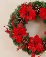 Extra thick red and gold pre-lit Christmas wreath styled on a wall with warm white lights