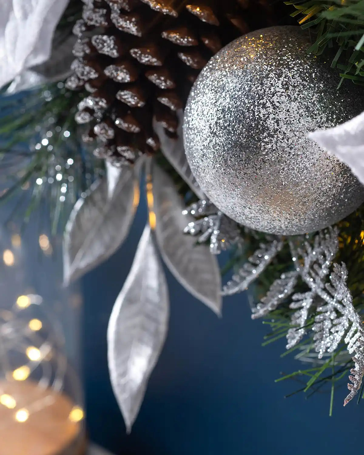 Detail of a silver bauble, frosted pinecone and silver leaves on the pre-lit Christmas wreath