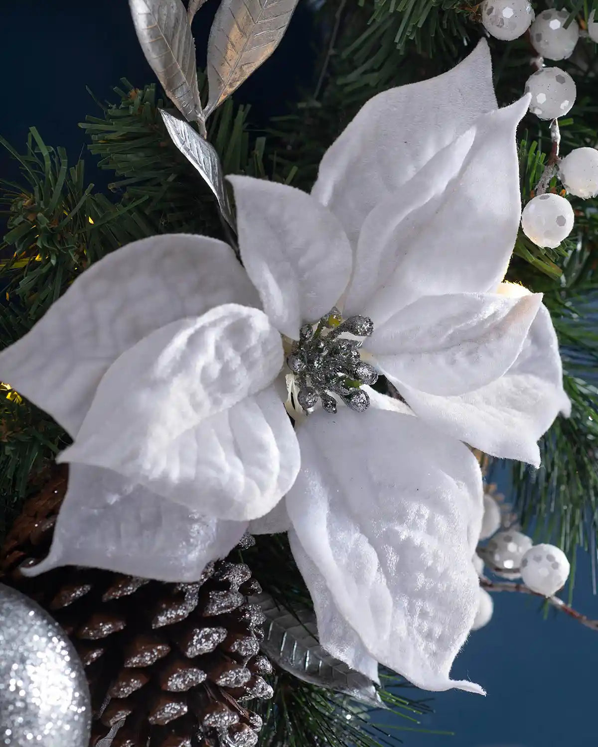 Close-up of a white poinsettia, berries and silver leaves on the pre-lit Christmas wreath