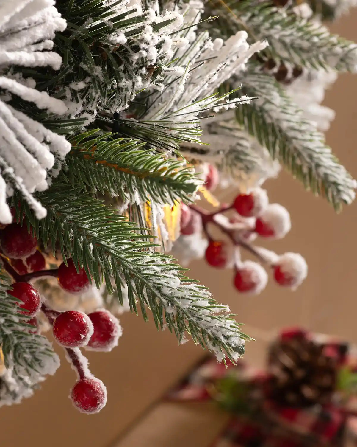 Detail of snow-flocked mixed pine foliage and red berries on the pre-lit Christmas wreath