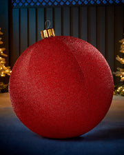 Large red 76cm inflatable tinsel Christmas bauble with a gold cap in an outdoor festive display.