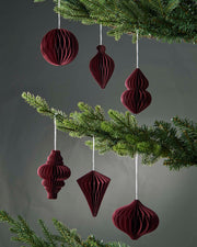 Maroon paper ornaments hanging on a Christmas tree against a dark background