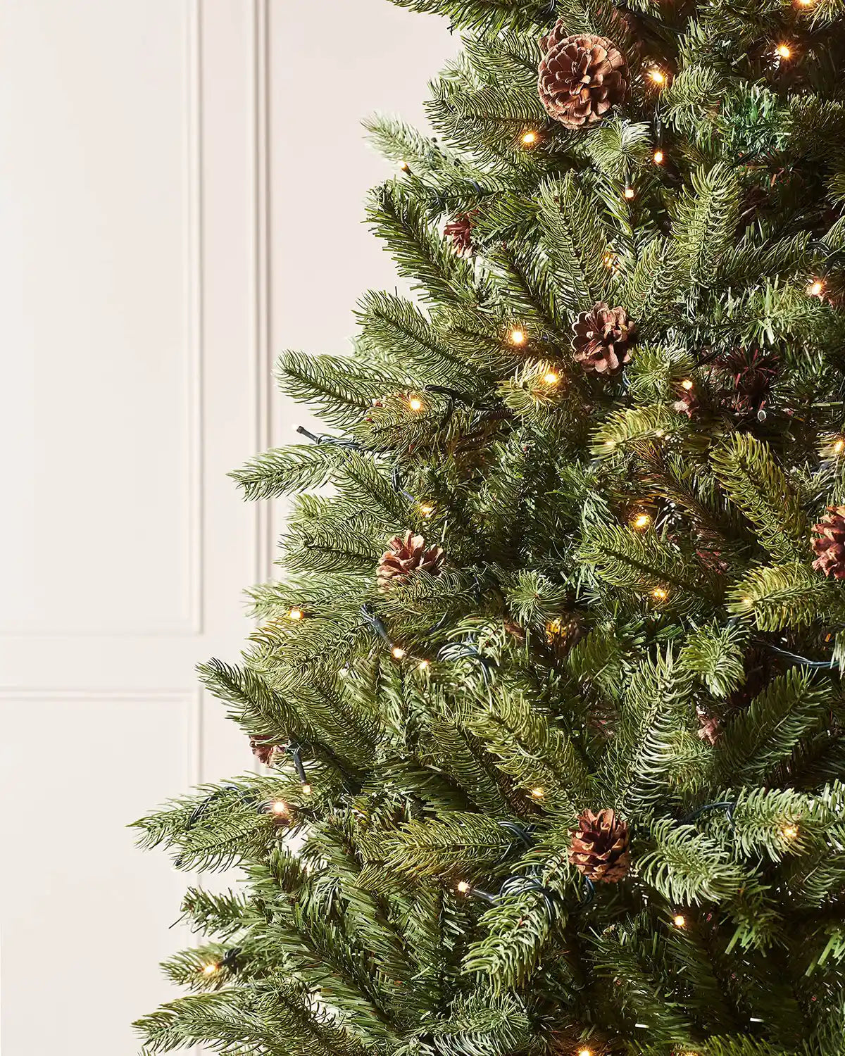 Close-up of realistic green branches, pinecones and warm white LEDs on a 7 ft Crawford pine Christmas tree