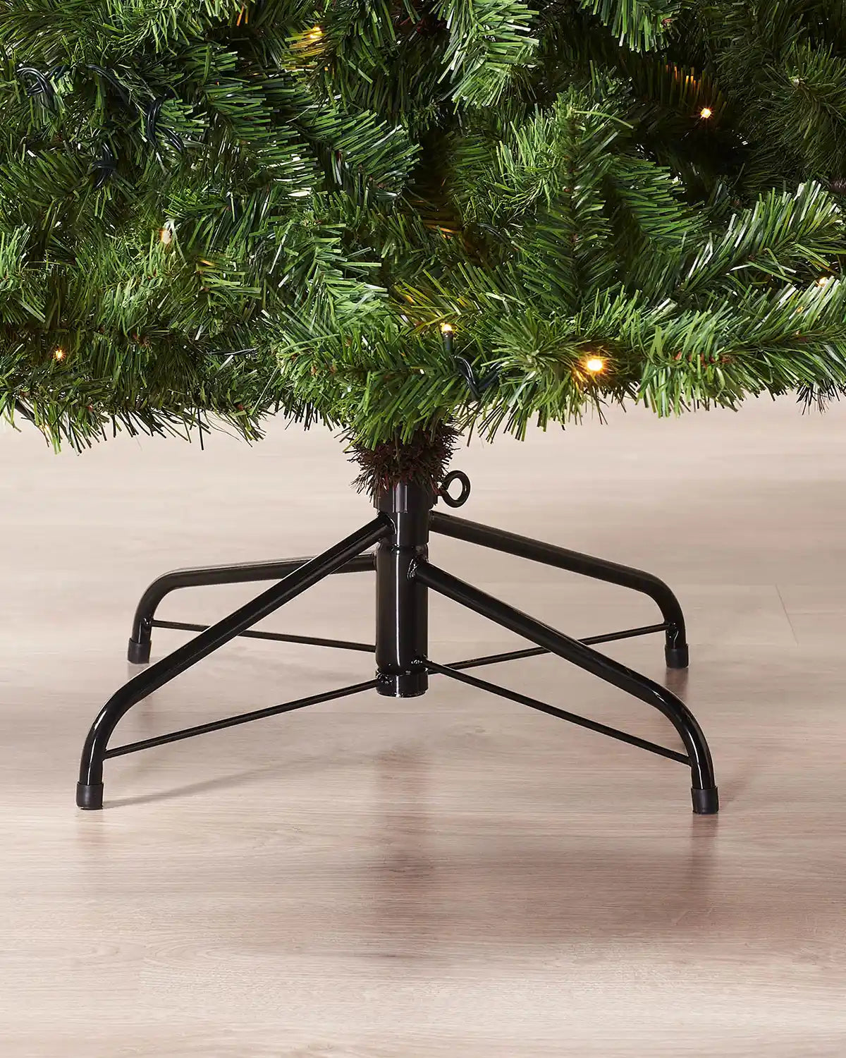 Close-up of the metal tree stand beneath a 7 ft pre-lit emerald spruce Christmas tree
