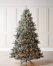 Pre-lit 7 ft full bodied snow flocked Christmas tree displayed indoors with warm white LEDs and a classic full silhouette