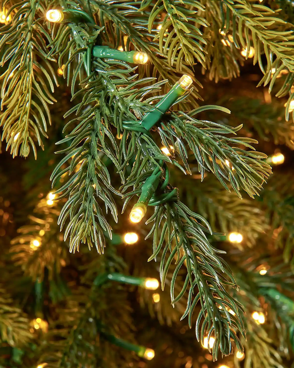Detail of warm white LED lights nestled among realistic green fir branches on the 7ft Highland fir Christmas tree.