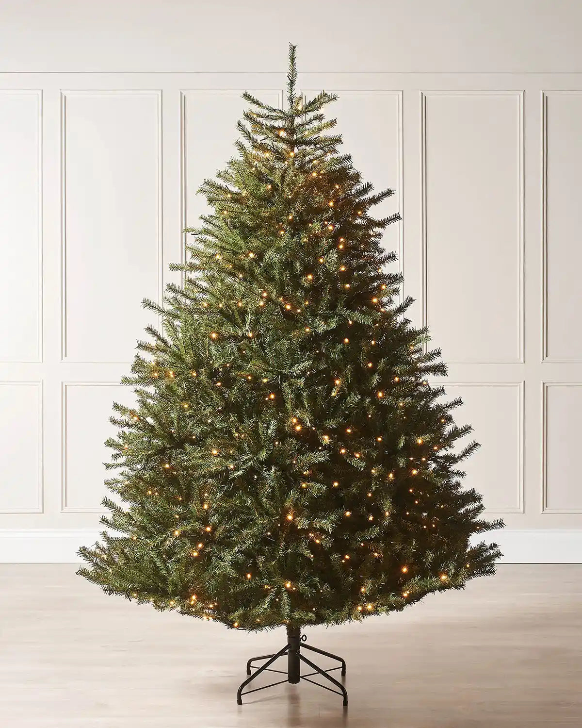 7ft Christmas tree with lights against a cream panel wall.