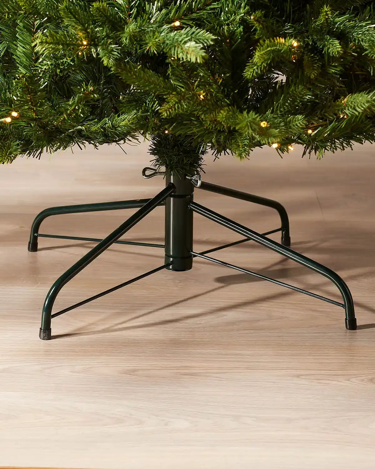 Close up of the base of 7ft Himalayan Fir Christmas tree with lights and Black Tree Stand