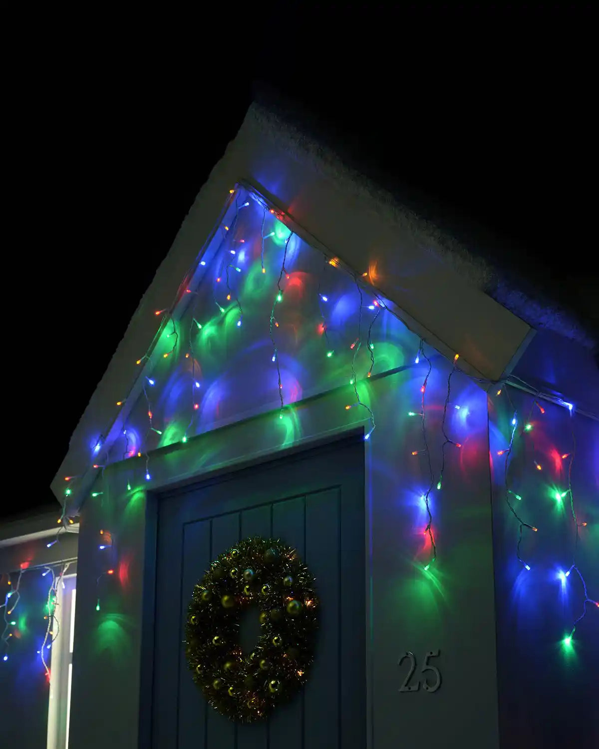 Multi-coloured icicle lights displayed above a front door at night