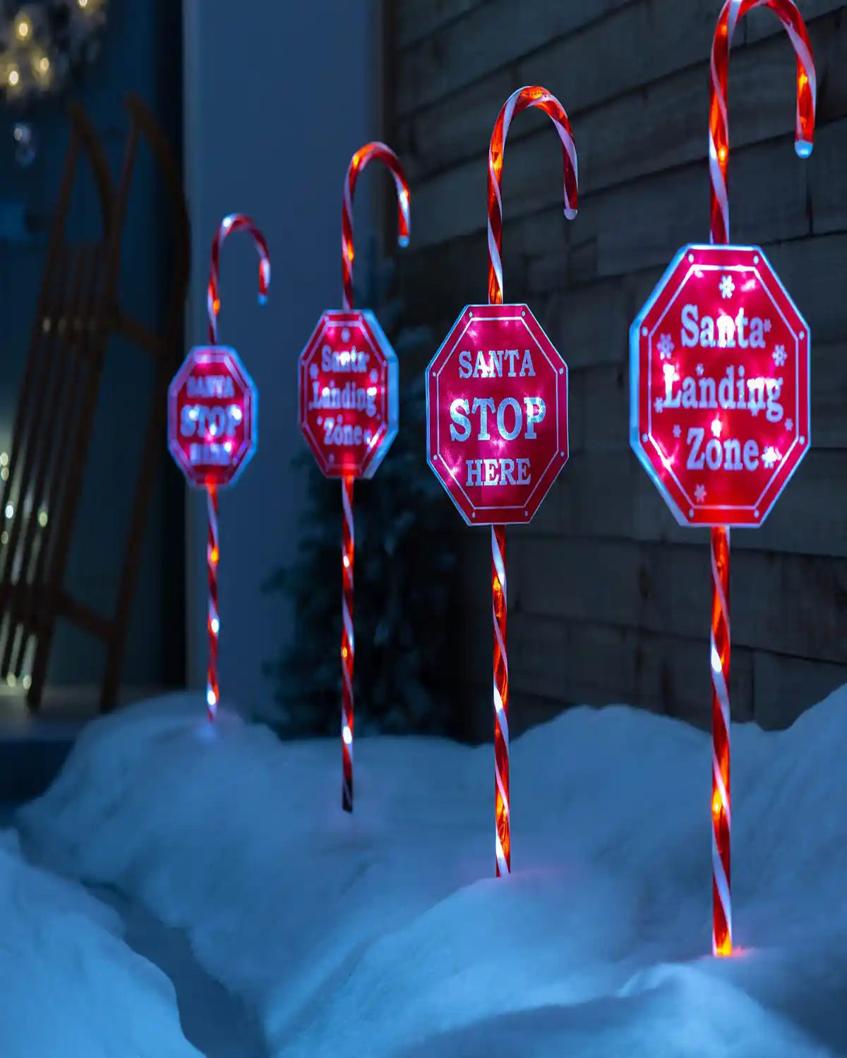 Set of 4 illuminated candy cane pathway stake lights displayed outdoors in snow
