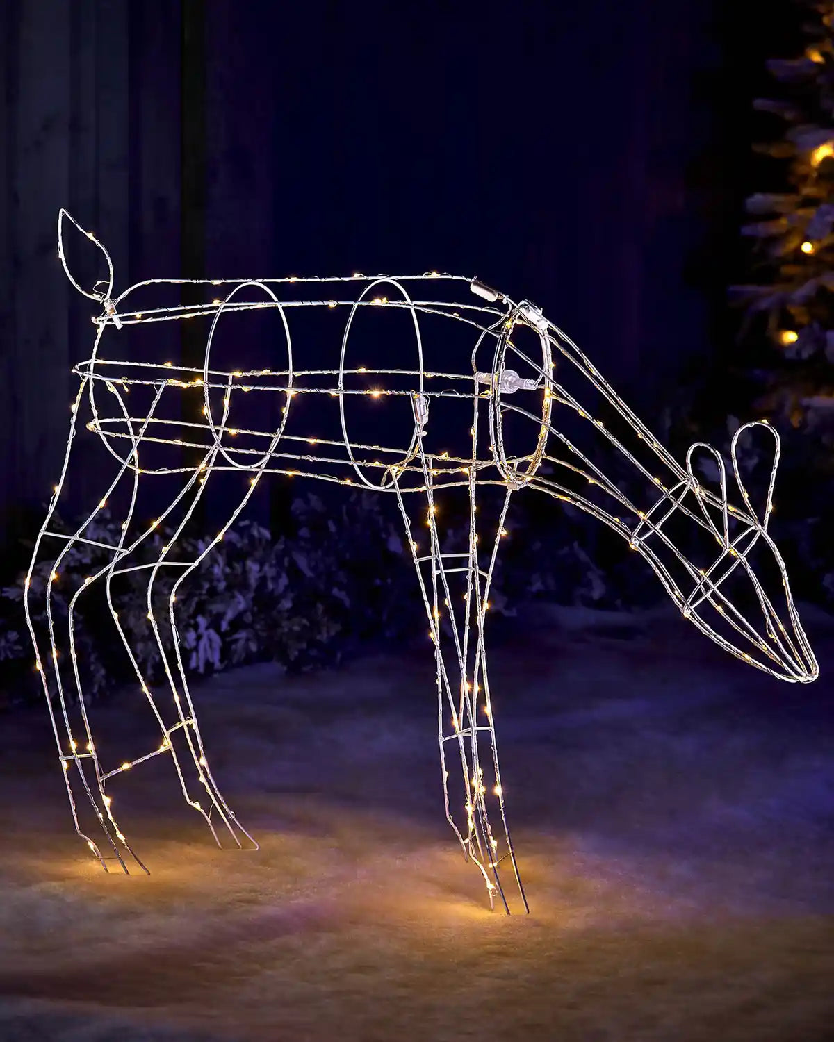 Illuminated 3D grazing reindeer decoration displayed outdoors at night