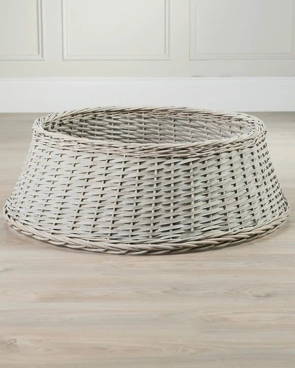 85cm grey wicker tree collar displayed indoors on a wooden floor, showing its tapered shape and open top.