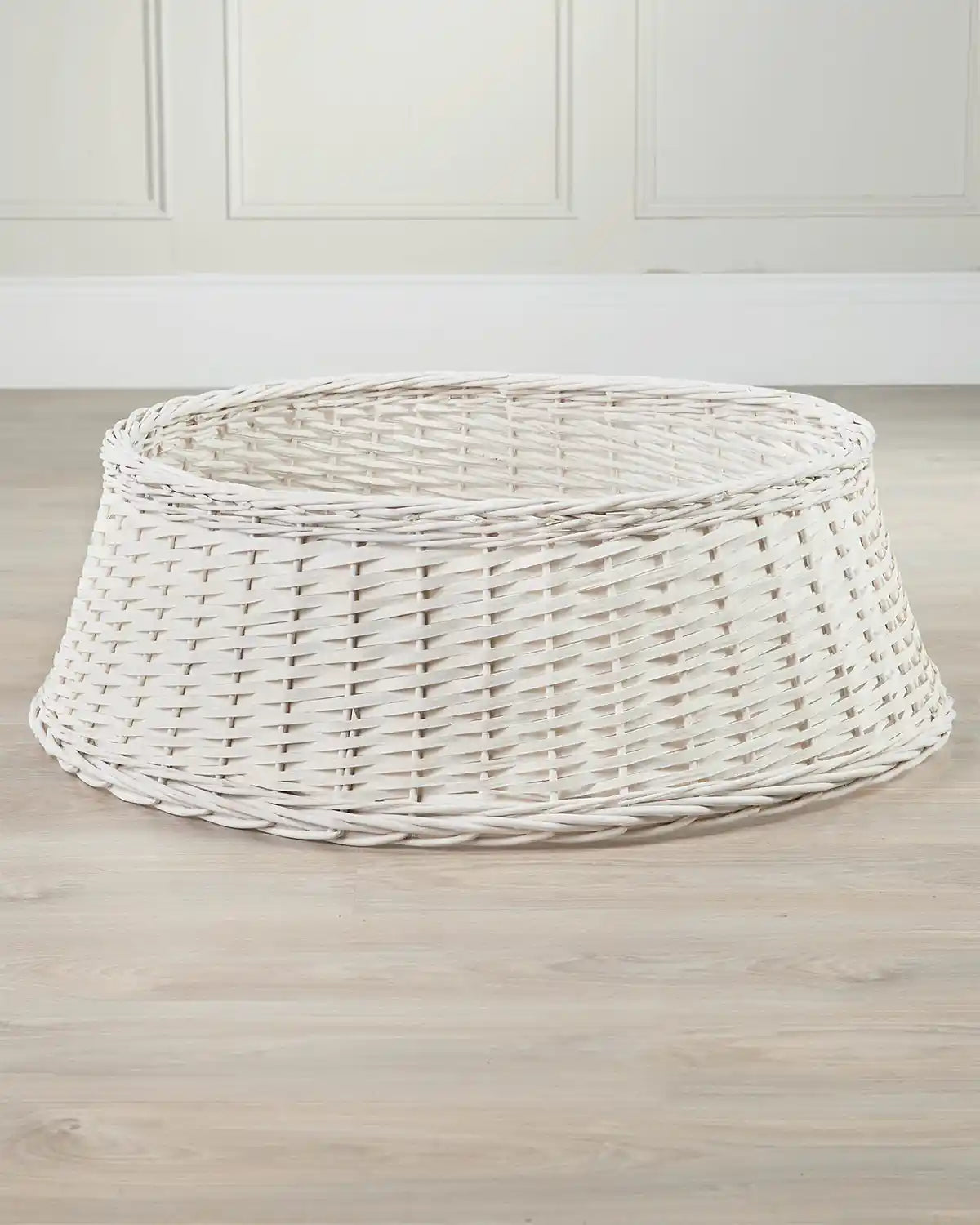 85cm off-white wicker tree collar displayed indoors on a wooden floor, showing its tapered shape and open top.