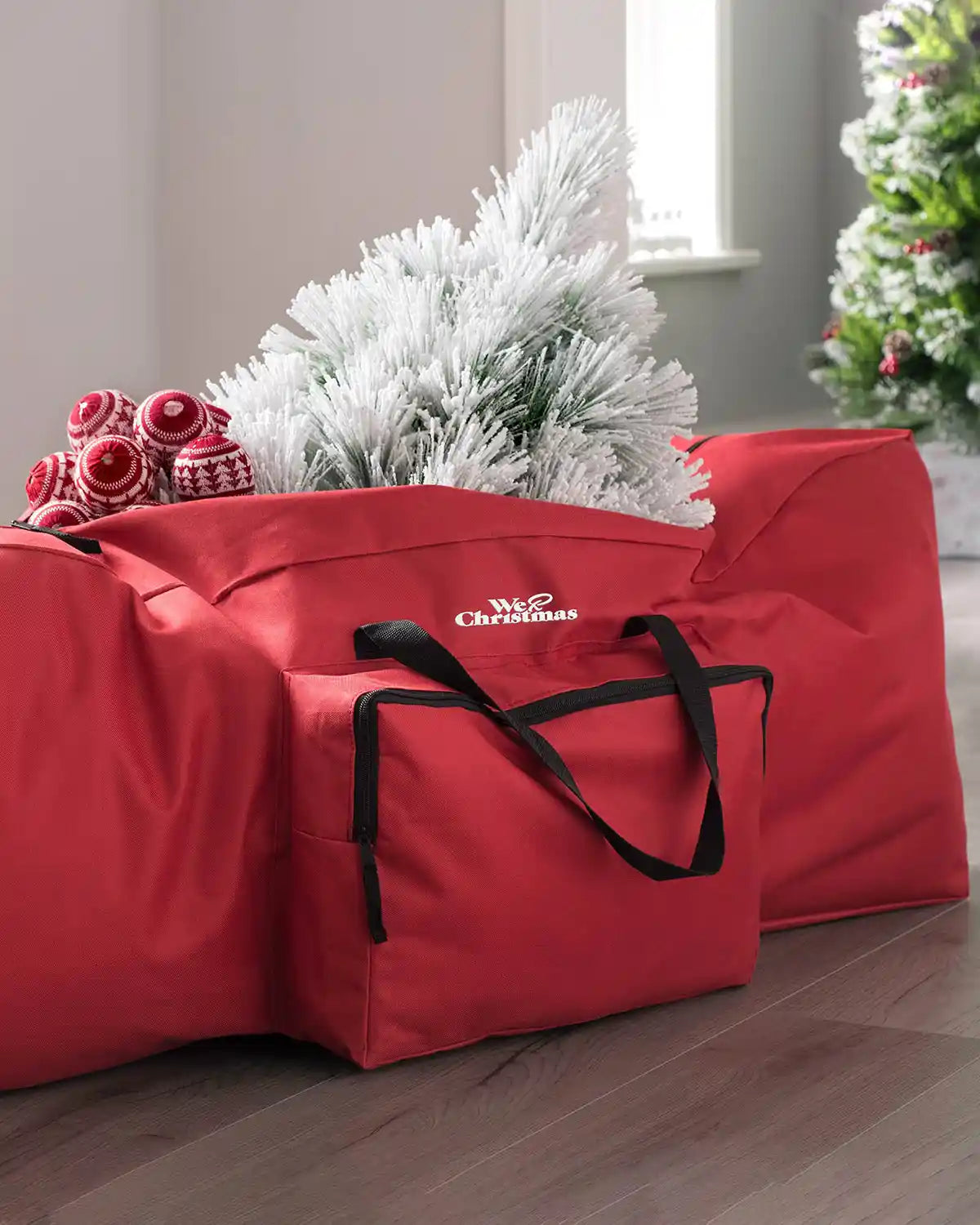 Red Christmas tree storage bag holding a flocked artificial tree indoors