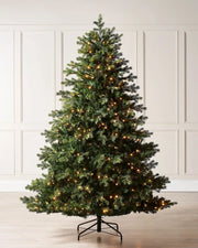 8ft pre-lit balsam fir Christmas tree with warm white LED lights, shown indoors on a metal tree stand.