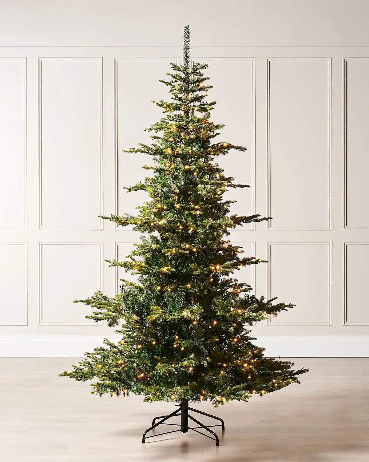8ft Christmas tree with lights on a cream panel background