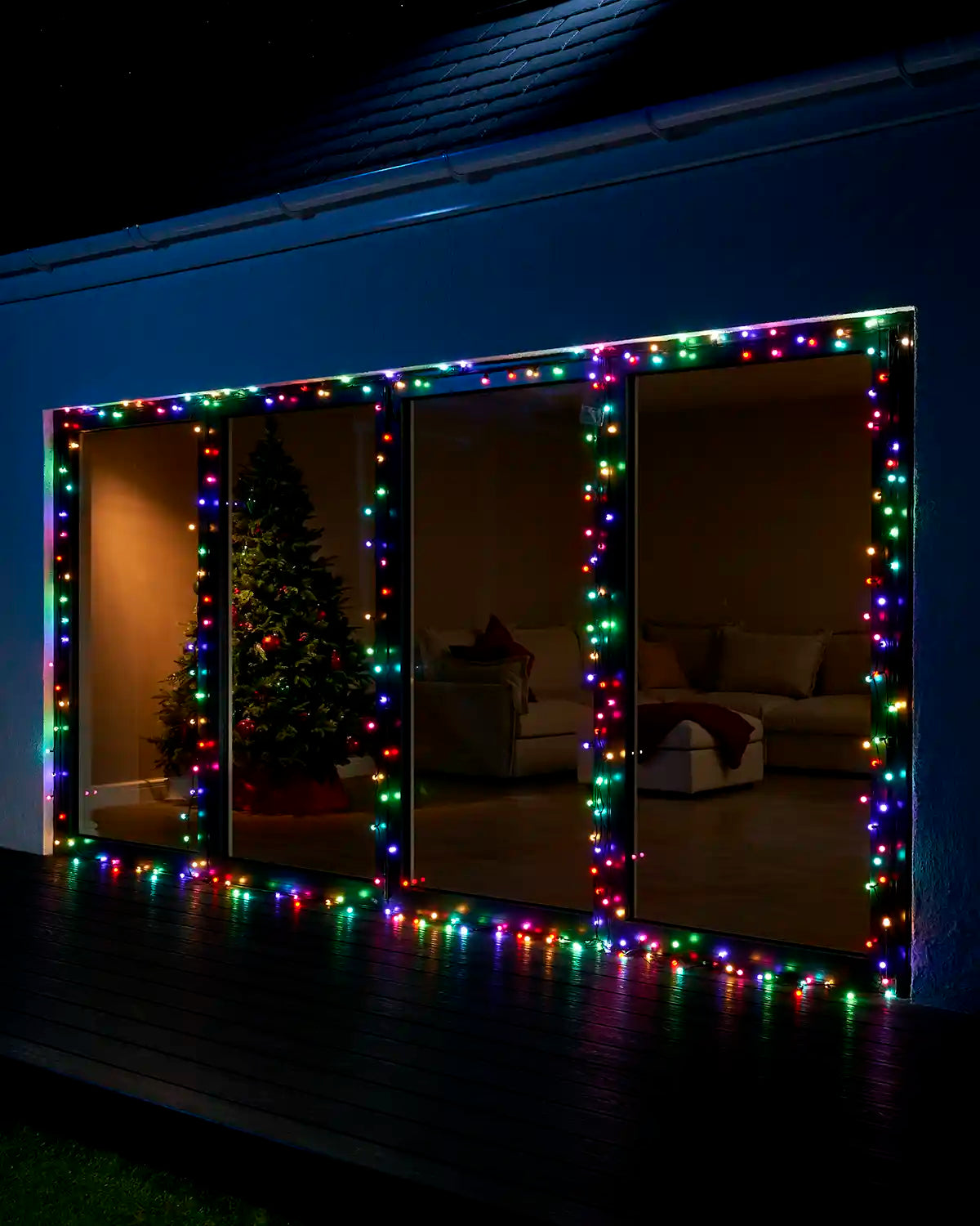 Multi-coloured berry lights framing large patio doors at night.