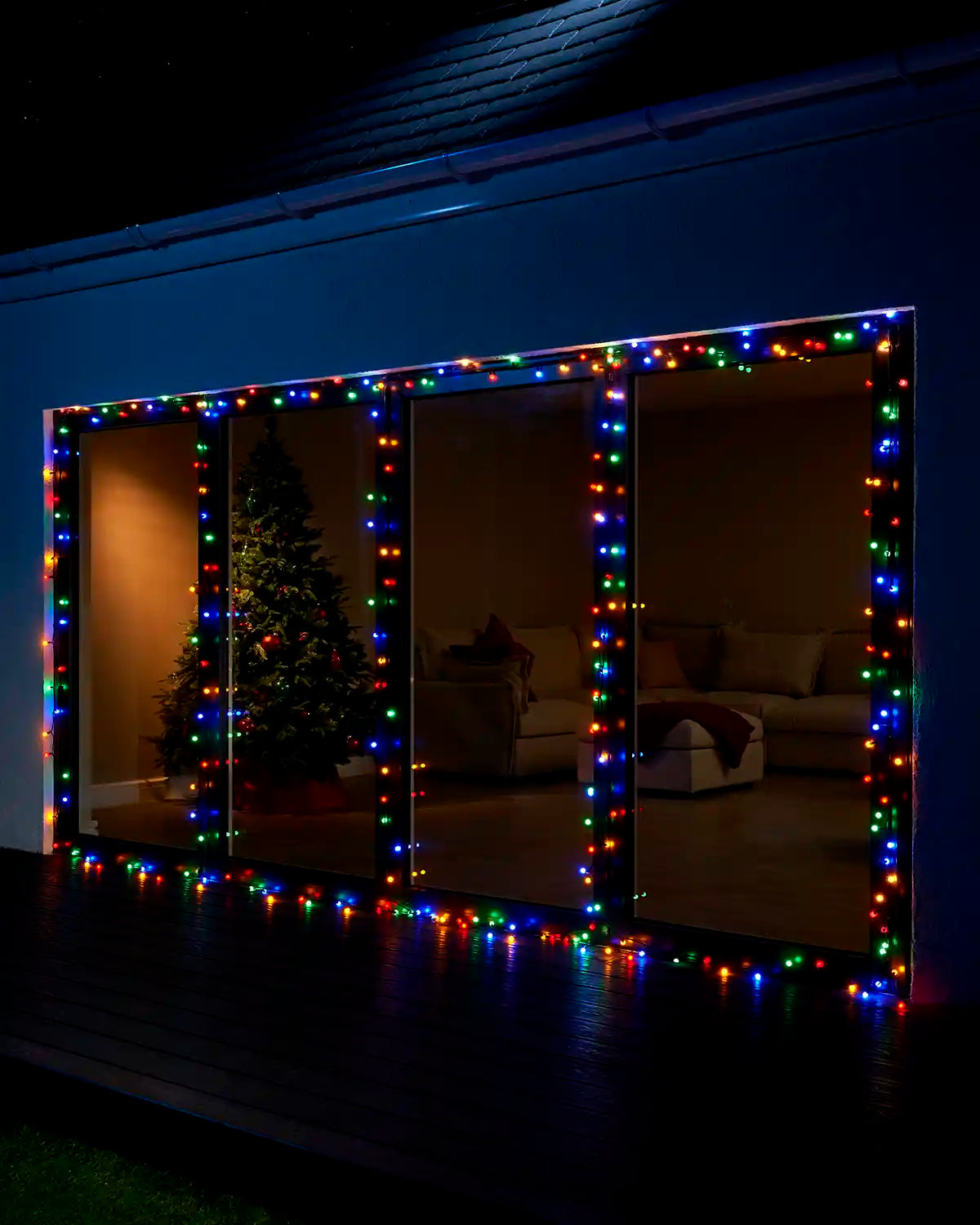 Multicolour berry lights framing large patio doors at night.
