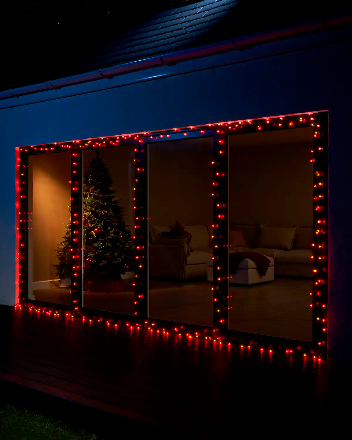 Red berry lights framing large patio doors at night.