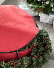Red garland and wreath storage bag holding a Christmas garland indoors