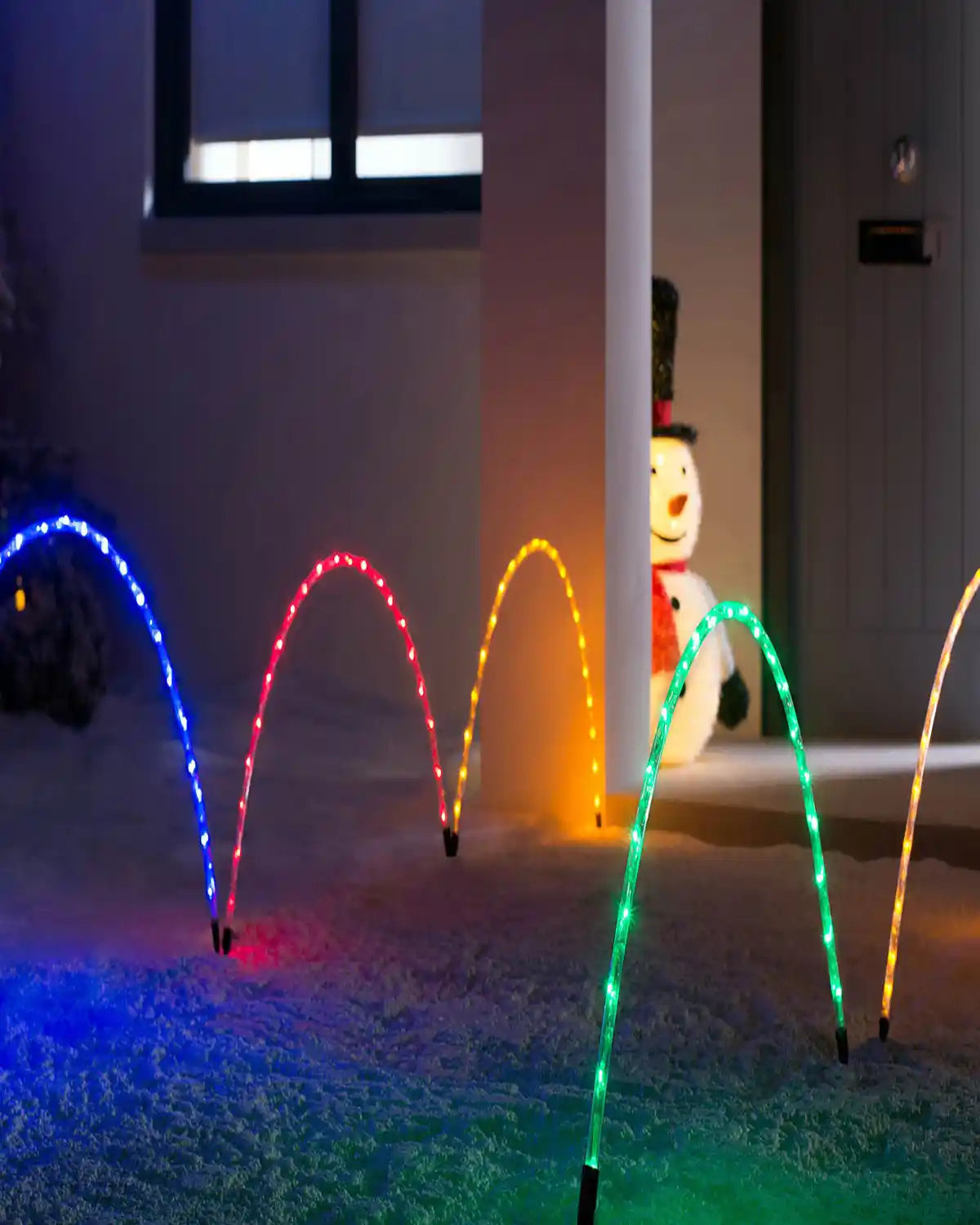 Outdoor Christmas display with 92 cm multicolour arch pathway chasing lights along a snowy garden path beside a festive doorway