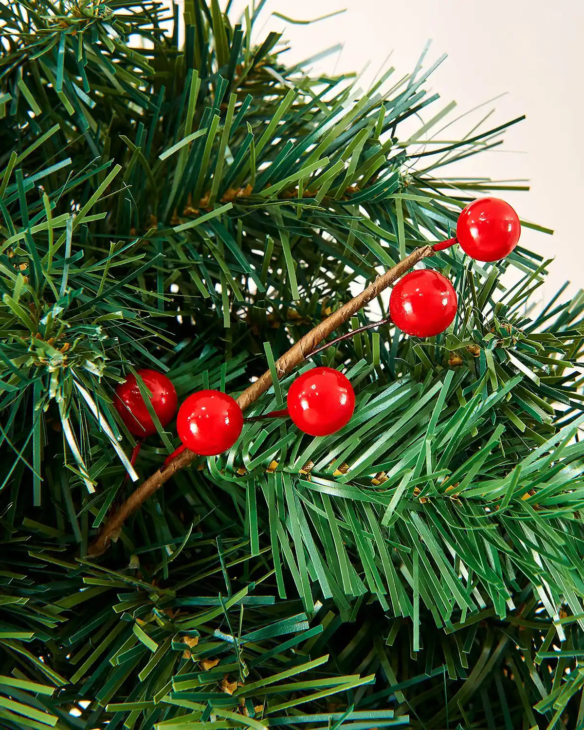 Close-up of glossy red berries on a green mixed pine Christmas garland