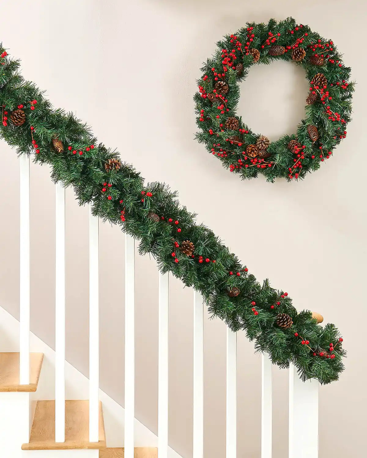 9ft green mixed pine garland with red berries and pine cones displayed on a white staircase bannister with matching wreath