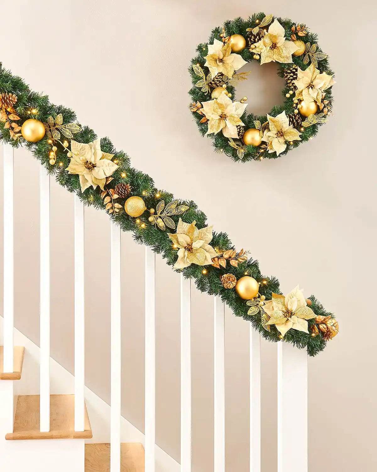 Pre-lit cream and gold Christmas garland displayed on a staircase with matching wreath and warm white LEDs