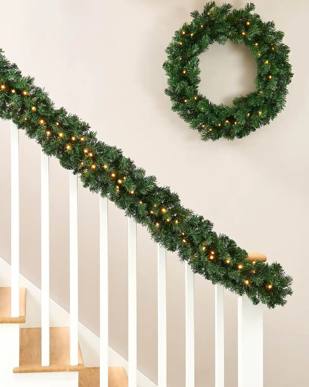 Pre-lit extra thick pine garland displayed on a staircase with matching wreath and warm white LEDs
