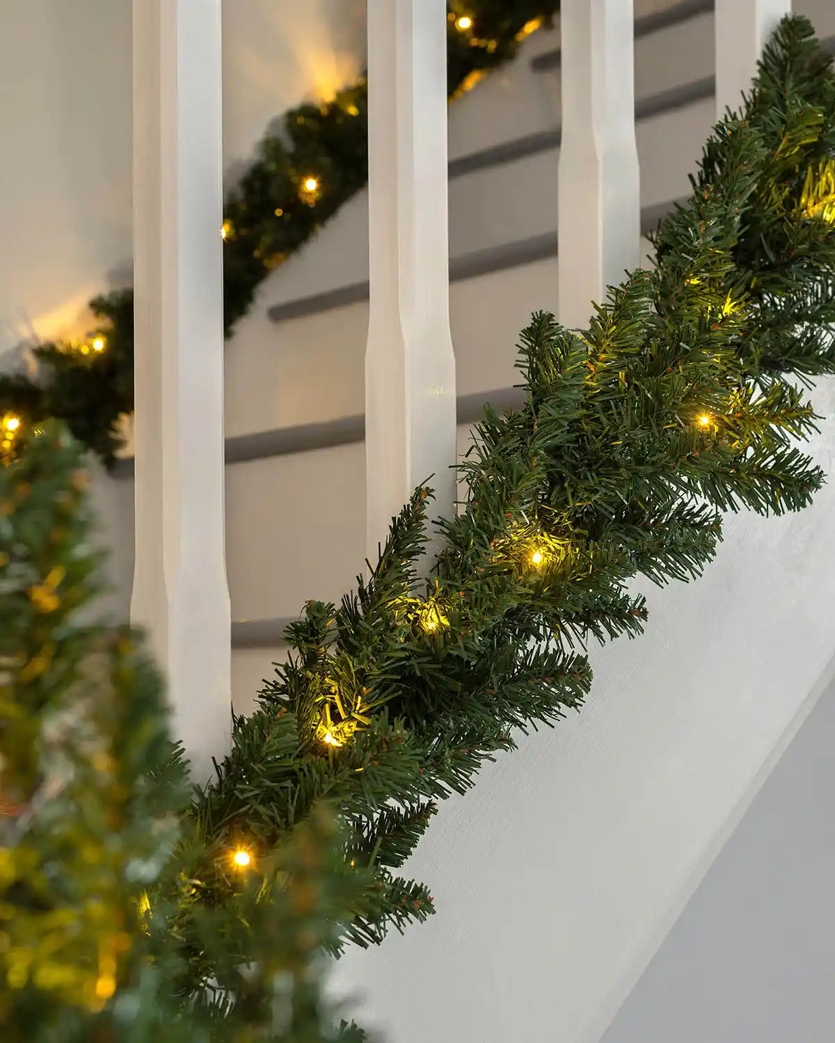 9 ft green pre-lit Christmas garland with warm white LEDs displayed along a stair rail