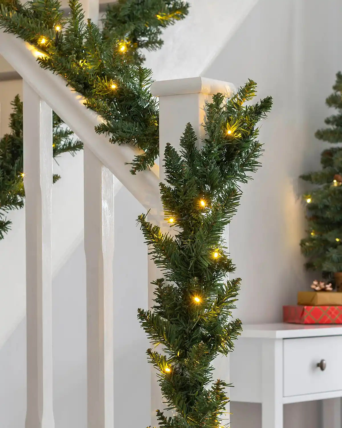 9 ft pre-lit Christmas garland with warm white LEDs wrapped around a staircase bannister