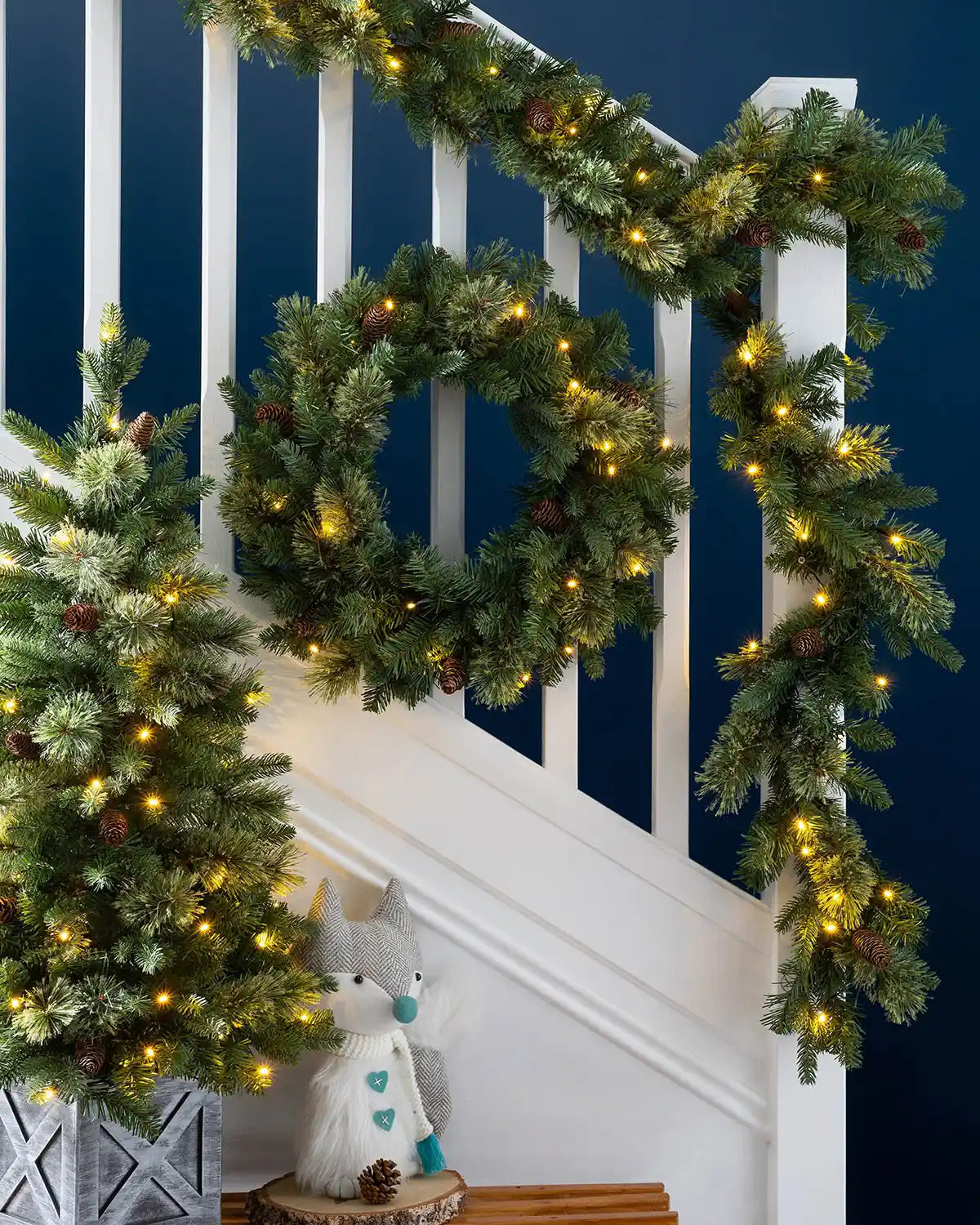 Natural pine Christmas garland wrapped along a staircase banister with warm white lights