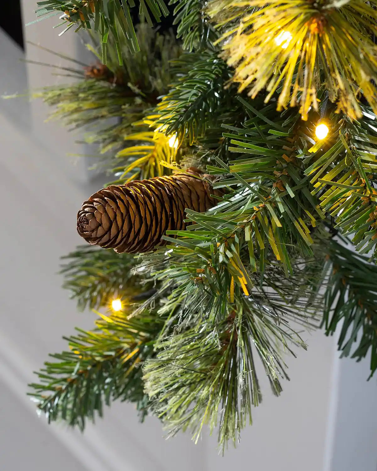 Close-up of a pinecone, mixed pine foliage and warm white lights on the natural pine garland