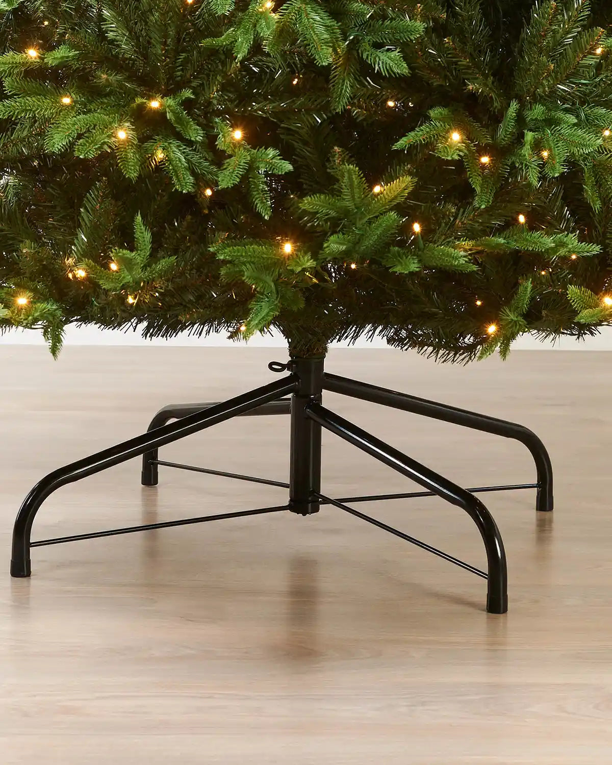 Close-up of the base of the 9ft pre-lit Royal Fir Christmas tree showing lower branches, warm white LEDs and metal tree stand.
