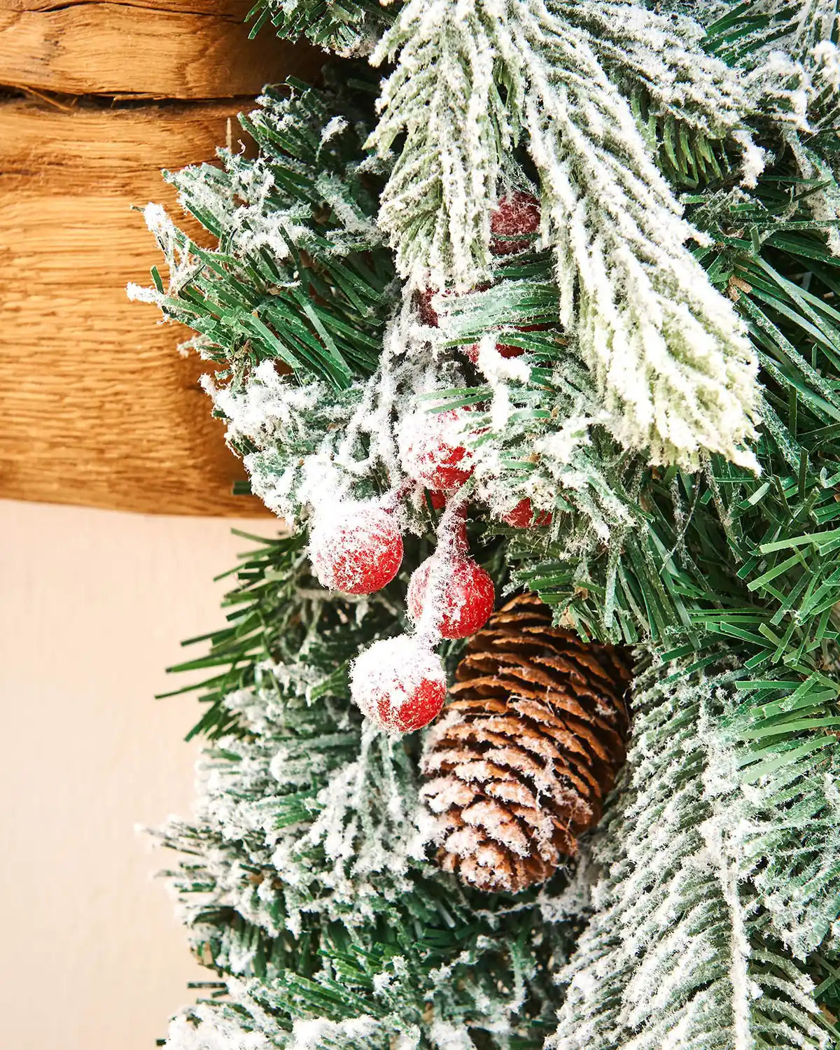 Close-up of snow flocked mixed pine garland with red berries and a pinecone