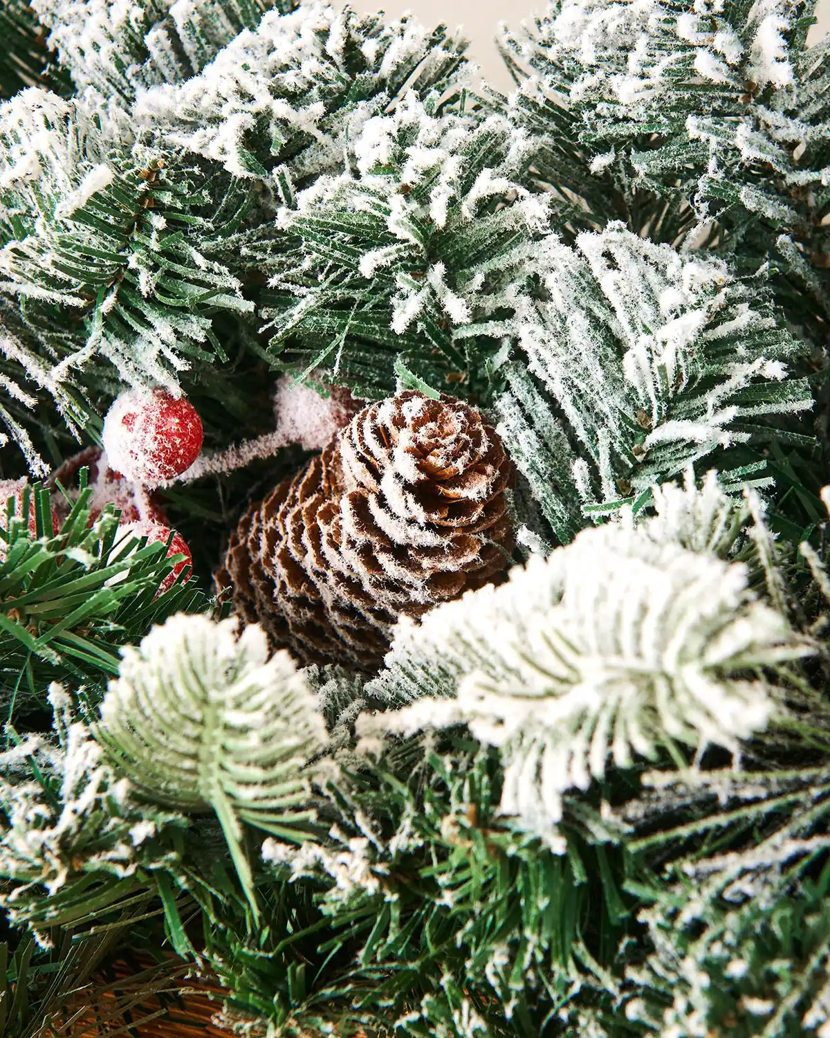 Detail close-up of a pinecone set among snow flocked mixed pine Christmas foliage