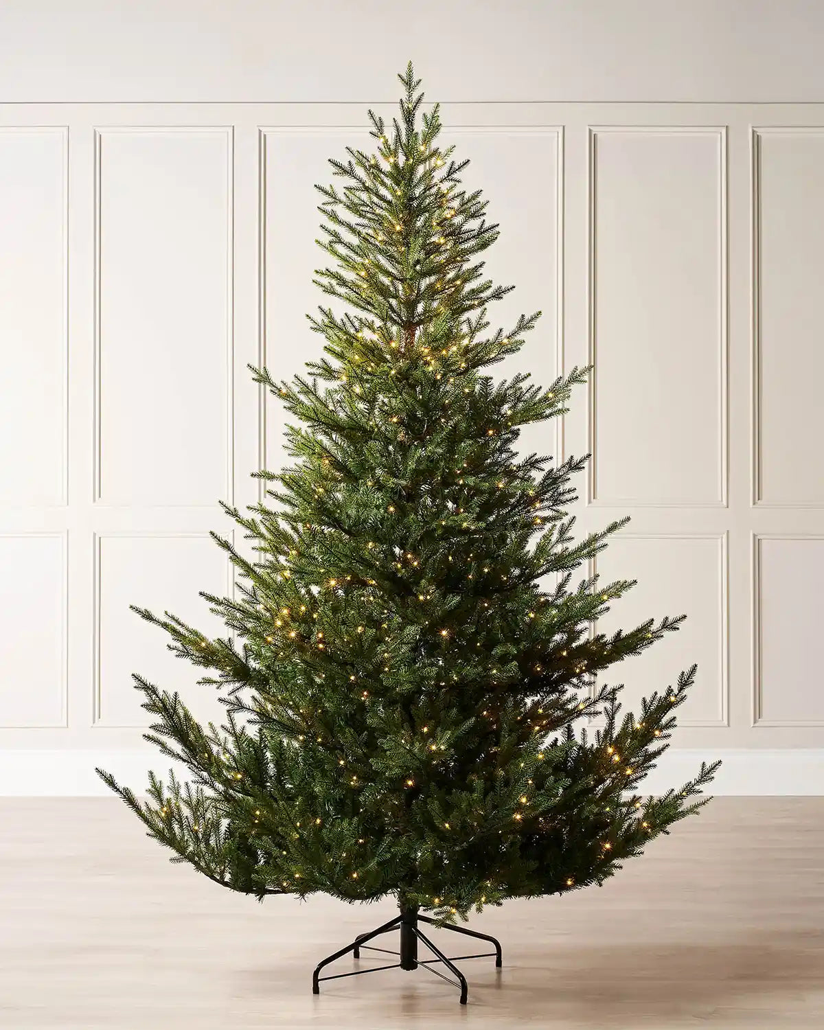 9ft Douglas Fir Decorated Christmas tree with lights against a cream panelled wall.
