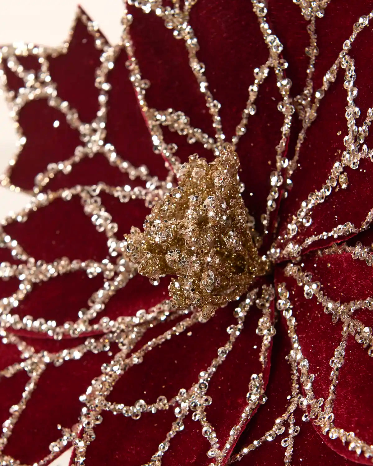 A close-up of a Burgundy velvet poinsettia-style decorative flower with Gold rhinestone trim and a glittery gold center.