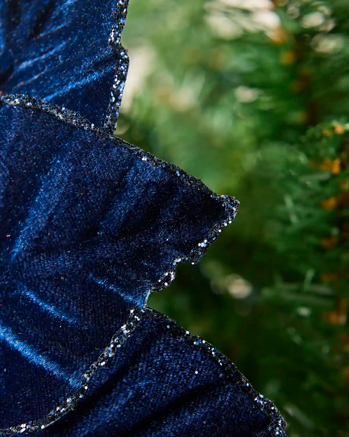 A close-up of a dark navy blue velvet  poinsettia with a textured, slightly glittery finish